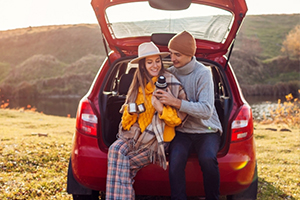 A man and girl are seated in the trunk of a car, smiling and enjoying their time together A man and girl are seated in the trunk of a car, smiling and enjoying their time together