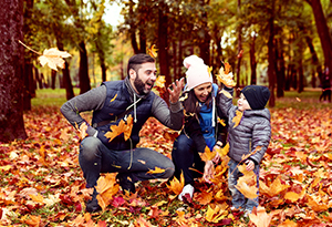 A family strolls through a colorful autumn forest, surrounded by vibrant fall foliage and tall trees A family strolls through a colorful autumn forest, surrounded by vibrant fall foliage and tall trees